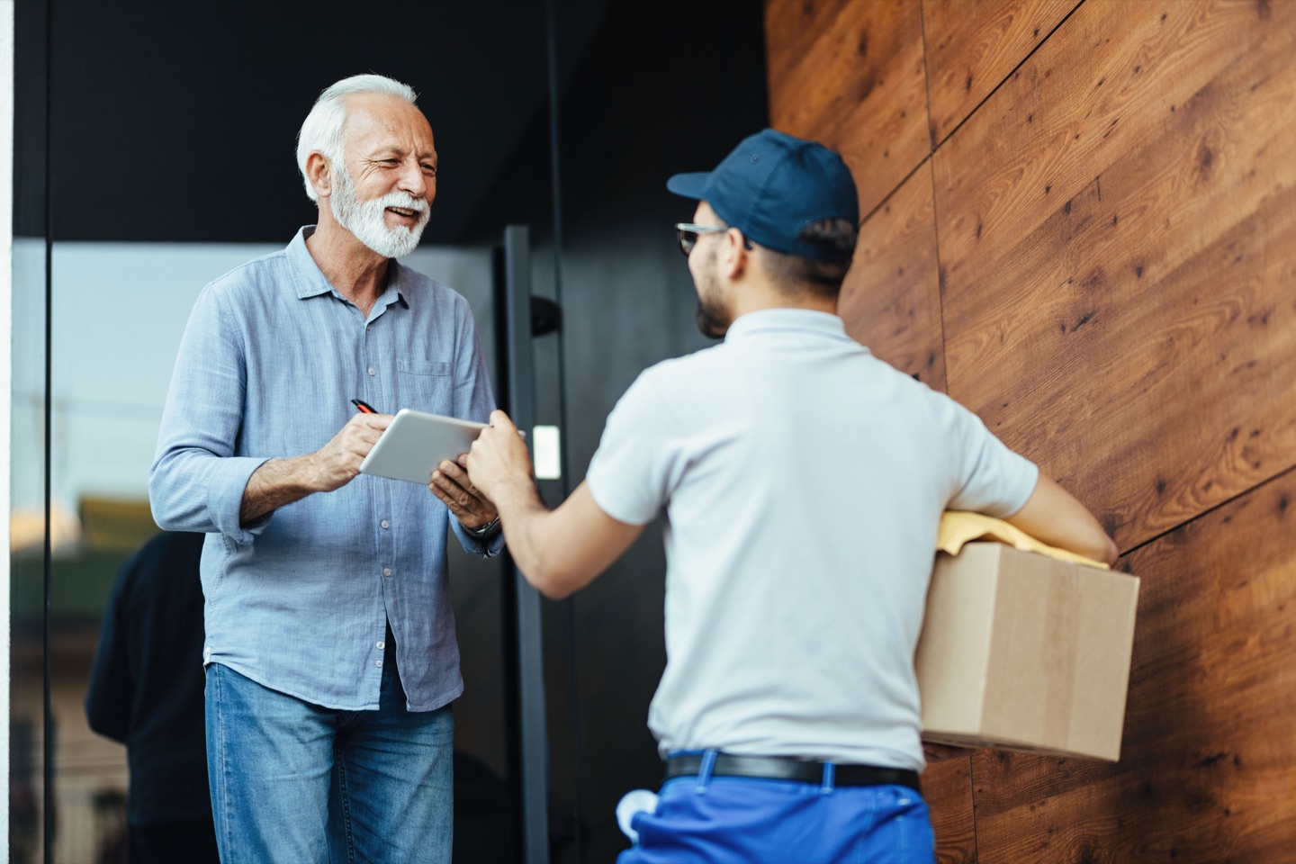 Delivery driver handing a tablet to a customer signing for a package