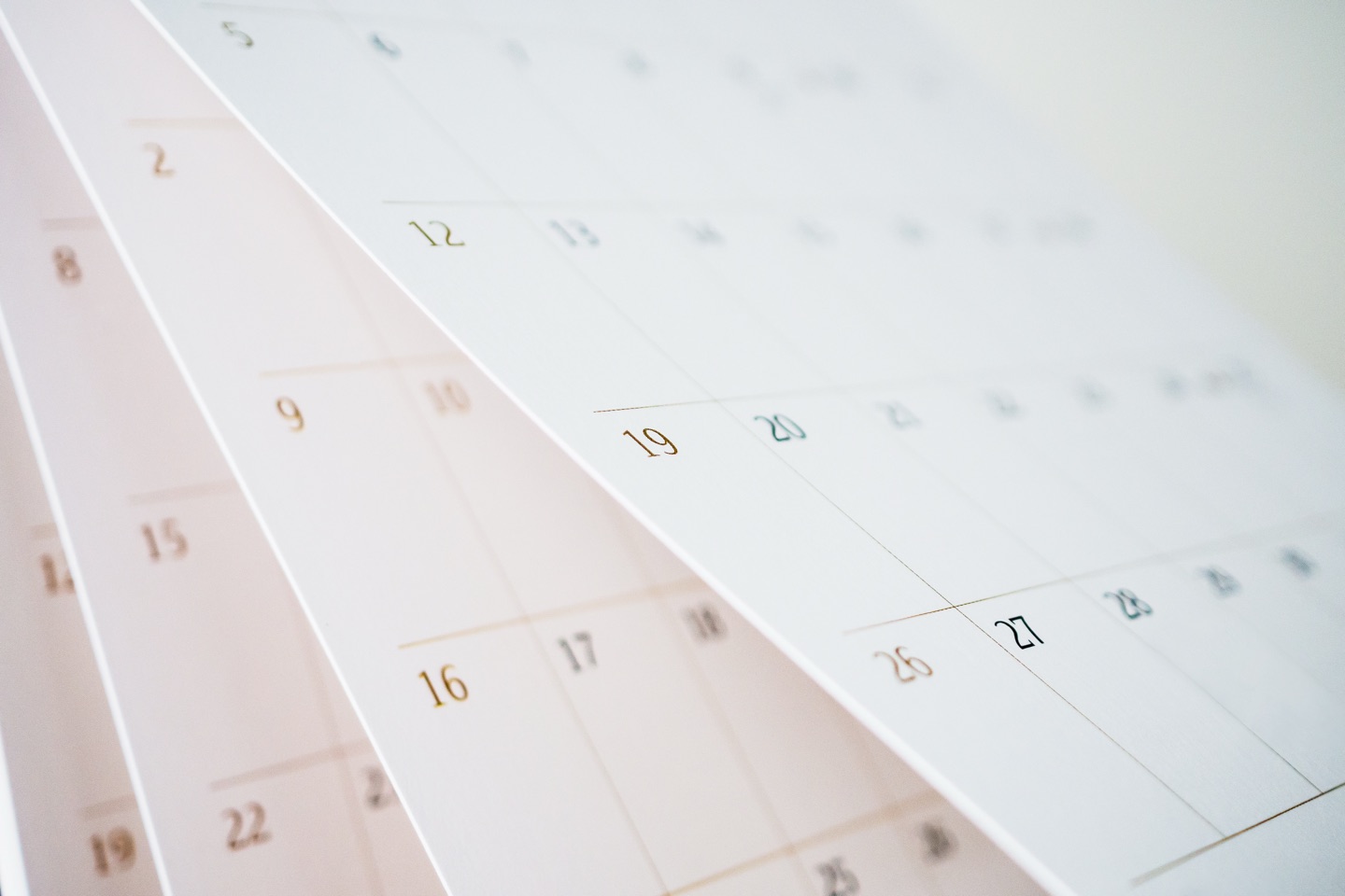Close-up of paper calendar pages fanned across a desk